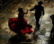 Prompt Midjourney : a spanish dance floor. a woman in a spanish red dress beckons a sly man to come dance the tango. the setting is dark, mysterious, and dangerous