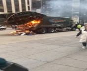 A garbage truck was ablaze in the middle of the street. Some trash spilled out as the fire raged inside the vehicle. Passerby watched in shock as the truck burned.